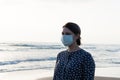 Young beautiful girl stands near the sea in a medical mask Royalty Free Stock Photo