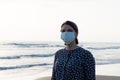Young beautiful girl stands near the sea in a medical mask Royalty Free Stock Photo