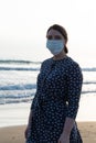 Young beautiful girl stands near the sea in a medical mask Royalty Free Stock Photo