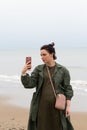 Young beautiful girl stands with a phone near the sea Royalty Free Stock Photo