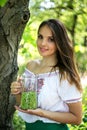 Young beautiful girl stands with a pitcher of green peas near the tree Royalty Free Stock Photo