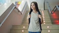 Young beautiful girl student wearing backpack going stairs down at school