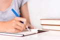 Young female student writes in notebook on desk with book Royalty Free Stock Photo