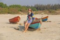 Young and beautiful girl in sunglasses, with blond hair, sitting on a boat, smiling on the beach and looking at the sea. A girl in Royalty Free Stock Photo