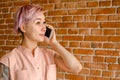 Young beautiful girl is talking on the mobile phone on a brick wall background Royalty Free Stock Photo