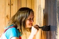 A young and beautiful girl with a tassel in her hands was very focused on painting the wooden surface in black paint.