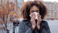 Young beautiful girl teenager millennial African American woman with curly hair stands in city on street suffers from