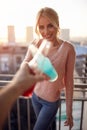 A young beautiful girl toasting and enjoying a drink with some company on the terrace of an apartment. Leisure, home, together