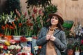 Young beautiful girl tourist looks in cameras and smiles near a store with flowers Royalty Free Stock Photo