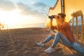 Young beautiful girl traveler sits on the beach and looks through binoculars. Travel Holidays Journey Concept Royalty Free Stock Photo