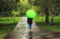 Young beautiful girl walking alone under green umbrella in the city park in summertime Royalty Free Stock Photo