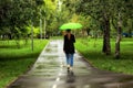 Young beautiful girl walking alone under green umbrella in the city park in summertime Royalty Free Stock Photo