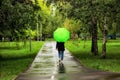 Young beautiful girl walking alone under green umbrella in the city park in summertime Royalty Free Stock Photo