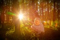 Young beautiful girl walking in forest and sun looking as star shining through the tree trunks. Model posing in the park in a Royalty Free Stock Photo