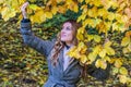 The young beautiful girl walks in the autumn park among yellow leaves in a coat on a sunny day Royalty Free Stock Photo