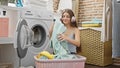 Young beautiful girl washing clothes listening to music at laundry room Royalty Free Stock Photo