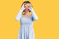 Young beautiful girl wearing casual clothes doing ok gesture like binoculars sticking tongue out, eyes looking through fingers Royalty Free Stock Photo