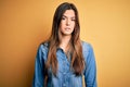 Young beautiful girl wearing casual denim shirt standing over isolated yellow background Relaxed with serious expression on face Royalty Free Stock Photo