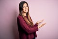 Young beautiful girl wearing casual sweater over isolated pink background Inviting to enter smiling natural with open hand