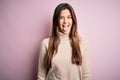 Young beautiful girl wearing casual turtleneck sweater standing over isolated pink background sticking tongue out happy with funny Royalty Free Stock Photo