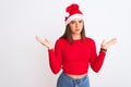 Young beautiful girl wearing Christmas Santa hat standing over isolated white background clueless and confused expression with Royalty Free Stock Photo