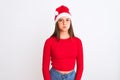 Young beautiful girl wearing Christmas Santa hat standing over isolated white background puffing cheeks with funny face Royalty Free Stock Photo