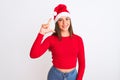 Young beautiful girl wearing Christmas Santa hat standing over isolated white background smiling and confident gesturing with hand Royalty Free Stock Photo