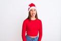 Young beautiful girl wearing Christmas Santa hat standing over isolated white background sticking tongue out happy with funny Royalty Free Stock Photo