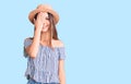 Young beautiful girl wearing hat and t shirt covering one eye with hand, confident smile on face and surprise emotion Royalty Free Stock Photo