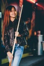 Young beautiful girl wearing leather jacket in a billiard club, with cue stick preparing for the game Royalty Free Stock Photo