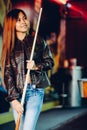 Young beautiful girl wearing leather jacket in a billiard club, with cue stick preparing for the game Royalty Free Stock Photo