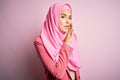 Young beautiful girl wearing muslim hijab standing over isolated pink background hand on mouth telling secret rumor, whispering Royalty Free Stock Photo