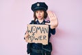Young beautiful girl wearing police uniform holding woman power banner with open hand doing stop sign with serious and confident Royalty Free Stock Photo