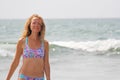 A young and beautiful girl, wearing sunglasses, in a beautiful separate swimsuit and blond hair, stands and smiles against the Royalty Free Stock Photo