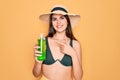 Young beautiful girl wearing swimwear bikini and summer hat holding alove vera sun protection very happy pointing with hand and