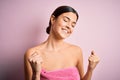 Young beautiful girl wearing towel shower after bath standing over isolated pink background very happy and excited doing winner
