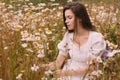 Young beautiful girl in white dress collecting flowers in chamomile field Royalty Free Stock Photo