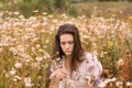 Young beautiful girl in white dress smelling flowers in chamomile field Royalty Free Stock Photo