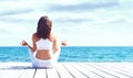 Young and beautiful girl in white sportswear doing yoga on a woo