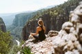 Young beautiful girl woman in black sporty slim outfit meditating on edge rock mountain cliff peak with view on valley Royalty Free Stock Photo