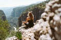 Young beautiful girl woman in black sporty slim outfit meditating on edge rock mountain cliff peak with view on valley Royalty Free Stock Photo