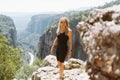 Young beautiful girl woman in black sporty slim outfit standing on edge of rock mountain cliff peak enjoying view of Royalty Free Stock Photo