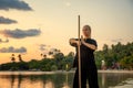 Young beautiful girl woman blond doing kung fu with bamboo stick on the seashore at sunset, fight Royalty Free Stock Photo