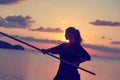 Young beautiful girl woman blond doing kung fu with bamboo stick on the seashore at sunset, fight Royalty Free Stock Photo