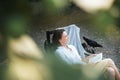 Young beautiful girl woman enjoys nature and reading a book in the summer in the garden of her house sitting on a chair Royalty Free Stock Photo