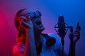 Young beautiful girl writes vocals, show business, DJ, get-together, pop music. In color light, blue-red and smoke Royalty Free Stock Photo