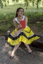 Young beautiful girl in a yellow dress with a book in the park. Reads, studies, rest Royalty Free Stock Photo