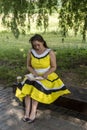 Young beautiful girl in a yellow dress with a book in the park. Reads, studies, rest Royalty Free Stock Photo