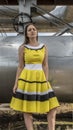 Young beautiful girl in yellow smart dress on a background of metal structures in the industrial zone, heating