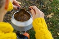 Young beautiful girl in a yellow sweater makes coffee in the forest on a gas burner. Making coffee on a primus stove in the autumn